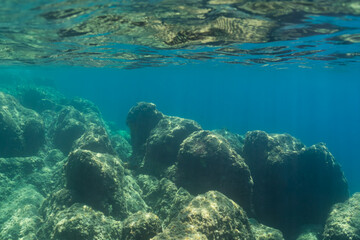 Fototapeta premium Beautiful underwater seascape with rocky bottom and clear turquoise water surface in Saint-Jean-Cap-Ferrat, French Riviera, Côte d'Azur, Mediterranean Sea.