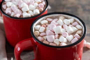 Hot chocolate drink with marshmallows in red mug on wooden table