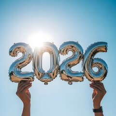 Celebrating the arrival of the New Year with shiny silver balloons displaying the number 2026 against a bright blue sky