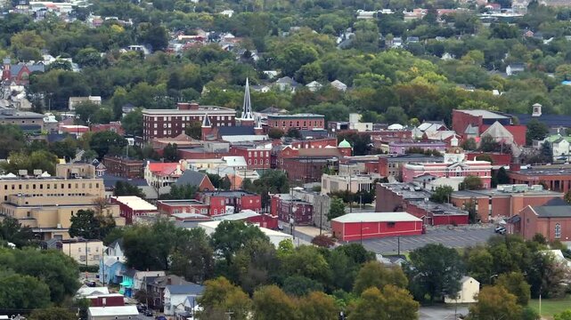 Establishing drone shot of Martinsburg Downtown in West Virginia during cloudy day in autumn season. Colored trees, church tower and red brick buildings. Historic old town in America. Wide shot.