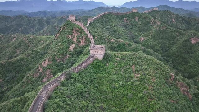Aerial view of the Jinshanling Great Wall snaking across verdant hills, a stone dragon amidst lush greenery, Jinshanling Great Wall, Jinshanling, China.