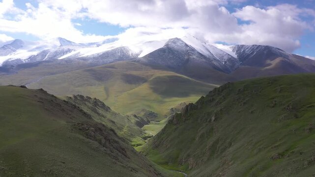 Sunny day aerial view of river valley in mongolia's altai mountin region with snowed mountains in the background on a sunny day