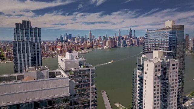 A cinematic drone shot rotating and rising above modern Brooklyn high-rise apartment buildings, revealing the Manhattan skyline and the iconic Empire State Building in the distance, of New York City.