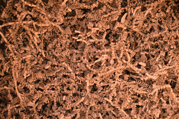 Close-up view of brown shredded paper packing filler filling the frame, showing textured crinkle strips and layered fibers used for protective packaging, gift cushioning and eco craft.