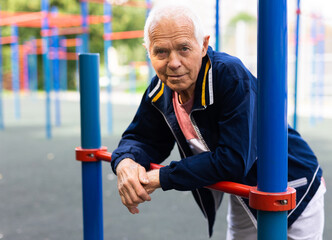 Obraz premium Portrait of sporty grandfather on playground in summer park