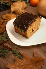 Slice of pumpkin pie with chocolate glaze. Autumn setting.