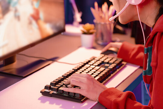 Host channel of young beautiful Asian gaming streamer playing fighting Moba at battle arena game on pc screen with multiplays, wearing pastel headphone at neon digital light modern room. Stratagem.