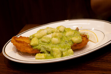 Crispy pan-seared sea bass fillet topped with Italian basil pesto sauce. A fine dining main course, plated beautifully with fresh herbs and chili.