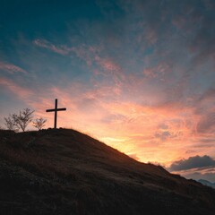 Fototapeta premium Sunset over a hilltop cross with a vibrant sky during dusk in a serene landscape
