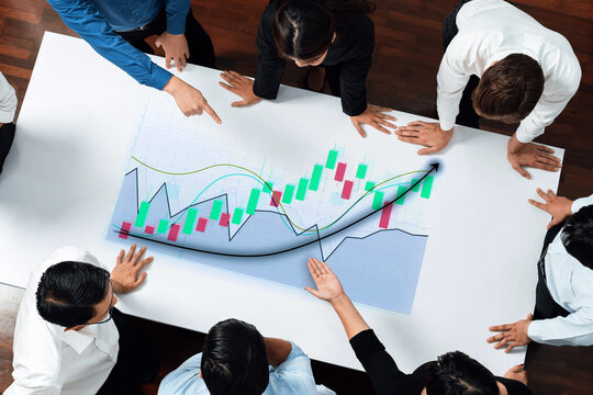 A collaborative business meeting showcases a diverse team of professionals analyzing data on a large chart, emphasizing teamwork and strategic planning in a modern office setting. Axiom