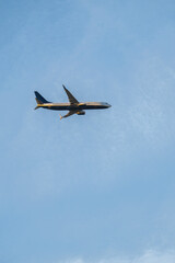 Airplane flying in clear blue sky with wispy clouds vertical