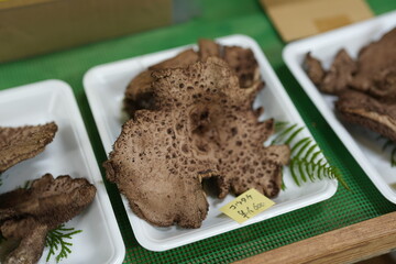 A plate of mushrooms with a yellow sticker that says 77460. The mushrooms are brown and have a rough texture