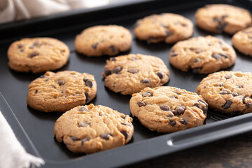 Baked chocolate chip cookies on a black baking tray