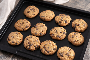 Baked chocolate chip cookies on a black baking tray