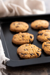 Baked chocolate chip cookies on a black baking tray
