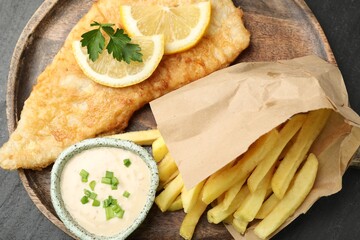 British Traditional Fish and chips with sauce, lemon and parsley on table, top view