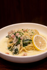 Creamy spaghetti with spinach and crispy bacon, topped with cheese. A classic, comforting Italian-American pasta dish. Close-up, top-down view.