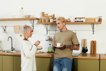 Young couple sharing a joyful moment over coffee in a cozy kitchen setting