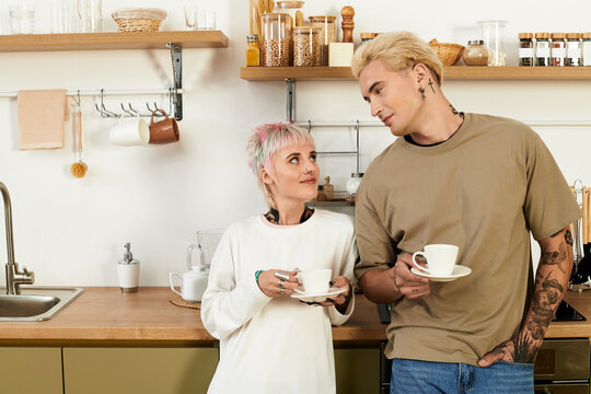 Young couple shares a joyful moment with coffee in a cozy kitchen setting - Powered by Adobe