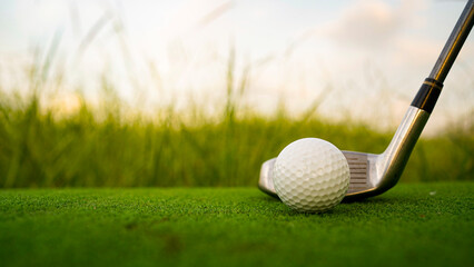 Golf clubs and balls on a green lawn in a beautiful golf course with morning sunshine.