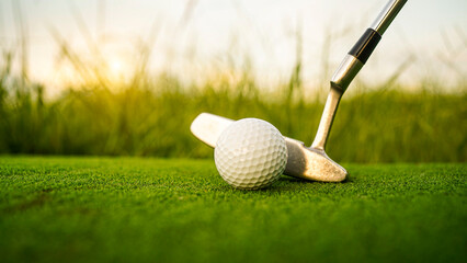 Golf clubs and balls on a green lawn in a beautiful golf course with morning sunshine.