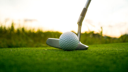Golf clubs and balls on a green lawn in a beautiful golf course with morning sunshine.