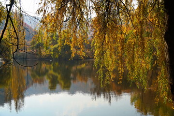Soldier Lake. A lake in a mountainous area with different vegetation. Bright juicy autumn leaves, leaf fall and reflection in the water.