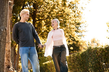 Young couple enjoys a joyful walk in a sunny park, sharing smiles and love