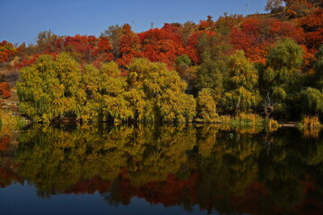 Soldier Lake. A lake in a mountainous area with different vegetation. Bright juicy autumn leaves, leaf fall and reflection in the water.