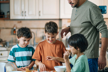Father and children preparing pizza together in home kitchen