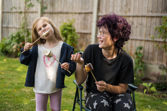 Sisters enjoying roasted marshmallows at a summer garden picnic bbq