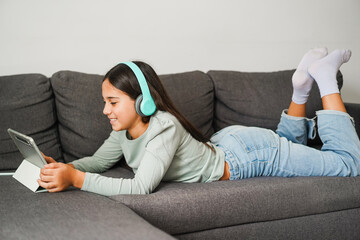 Female teen using tablet while drawing sitting on home sofa - Technology and teenager lifestyle concept - Main focus on face