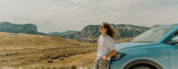 The confident woman enjoying a scenic view by her car in the mountains.