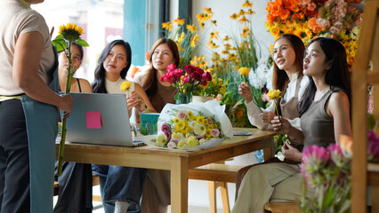 Diverse group of young people arranging flowers in florists workshop while attending class on floral art