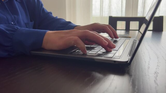 Close-up shot of human hands typing on a sleek laptop in a bright home workspace. Symbol of digital lifestyle, communication, productivity, freelance job and online business. Ideal for concepts of rem
