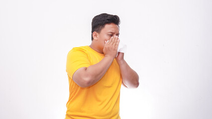 Asian fat man cover his nose and mouth with tissue when sneezing against white background