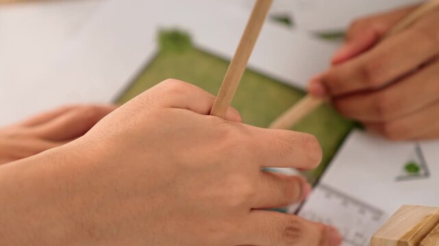 A video of architect using ruler and pencil to measure blueprint scale. Designer designing house construction on a table at studio with architectural plan scattered around. Focus on hand. Delineation.