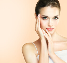 Beautiful young  smilling woman with clean fresh skin .She gently touches her face with her hands....