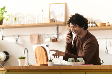 Handsome young man enjoying a cheerful conversation in a bright kitchen