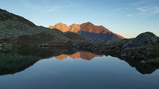 Aerial view of majestic mountains reflecting in the calm lake, a serene landscape with contrasting light and shadow, Medel (Lucmagn), Graub&uuml;nden, Switzerland.