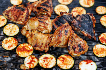 Barbecue chicken and zucchini cooking on outdoor grill