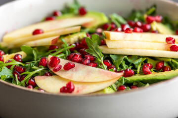 fall salad with arugula apple pomegranate and caramelized pecans close up