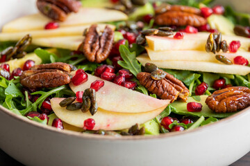 fall salad with arugula apple pomegranate and caramelized pecans close up