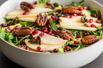 fall salad with arugula apple pomegranate and caramelized pecans close up
