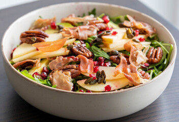 fall salad with arugula apple pomegranate and caramelized pecans close up