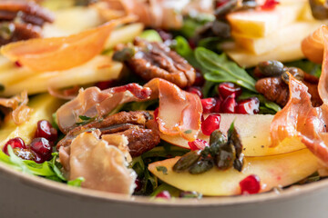 fall salad with arugula apple pomegranate and caramelized pecans close up