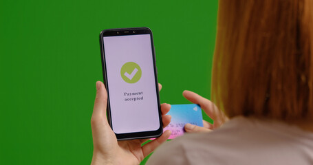 Woman with credit card in hand buying online on green screen background. Easy payment by online banking.