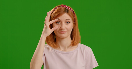 Woman sleepy holds her eyelids from closing in front of green screen background. Female trying to open eyes with fingers, sleepy, tired for morning fatigue. In need of some sleep.