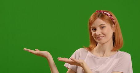 Happy woman face shows flat palms at commercial promotion or advertising copy space or marketing mockup over green screen background.