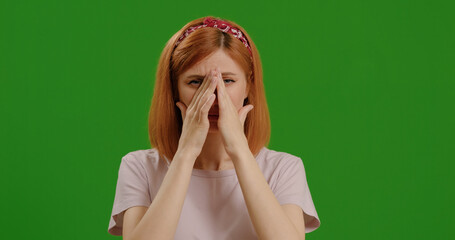 Woman touches her nose tries to sneeze on green background. Difficulty breathing, clogged nasal...